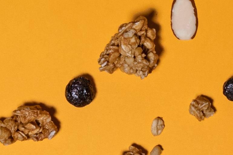 A orange background with scattered granola and raisins