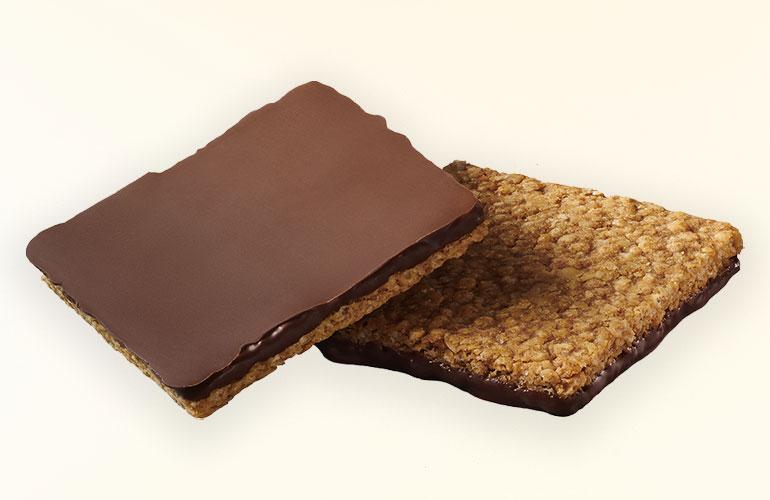 Two chocolate crunchy dipped granola squares one is upside down showing the chocolate layer.